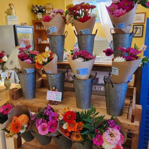 Rows of fresh market bouquets wrapped in kraft paper with labels in a farm store