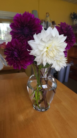 Purple and white dahlias in a glass vase atop a wooden table